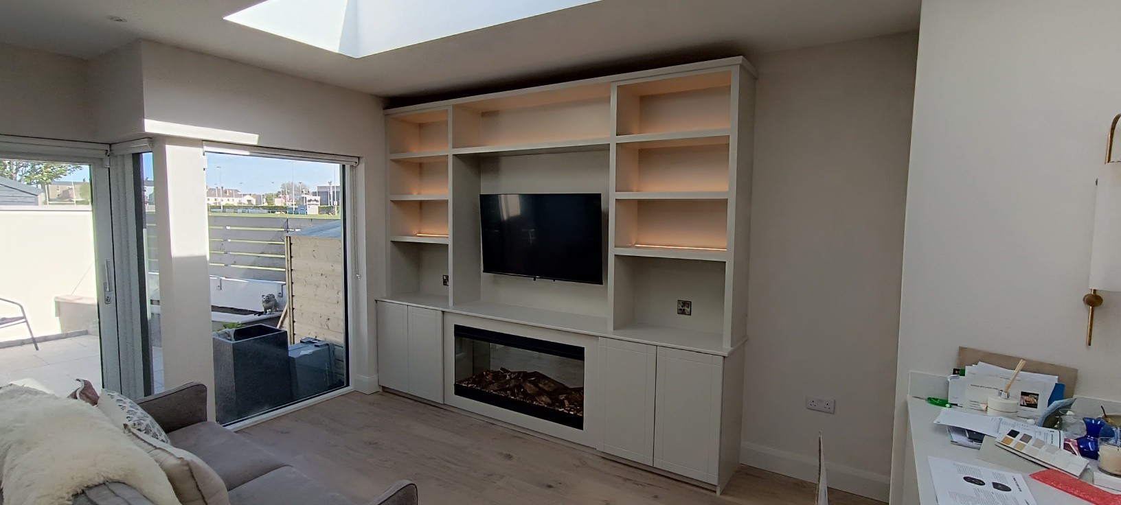 Bespoke media unit with shelving, TV and fireplace beside patio doors